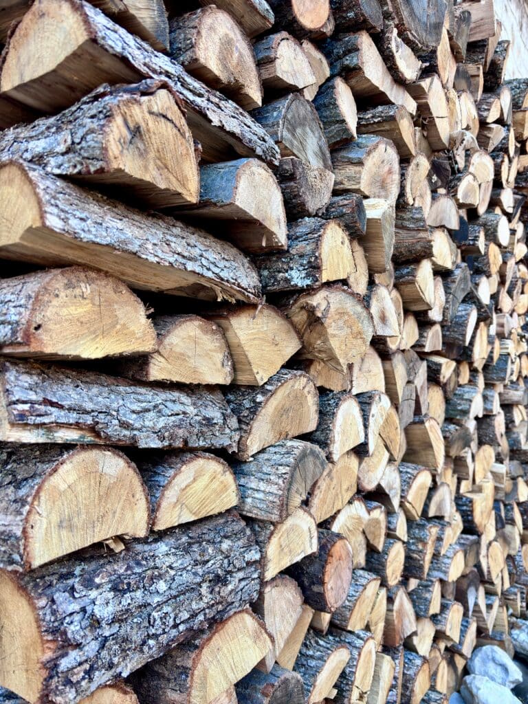 Bois de chauffage : Bûches fendues empilées pour l'hiver Pile dense de bois de chauffage fendu, bûches empilées révélant les textures d'écorce rugueuse et les couleurs du bois coupé.